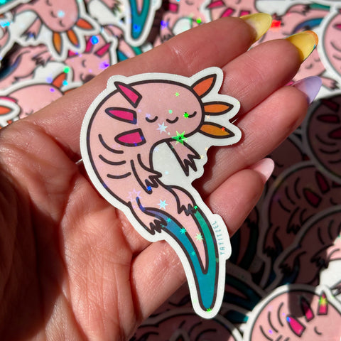 holding one colorful axolotl holographic sticker. it has holographic foil that sparkles in the shape of stars