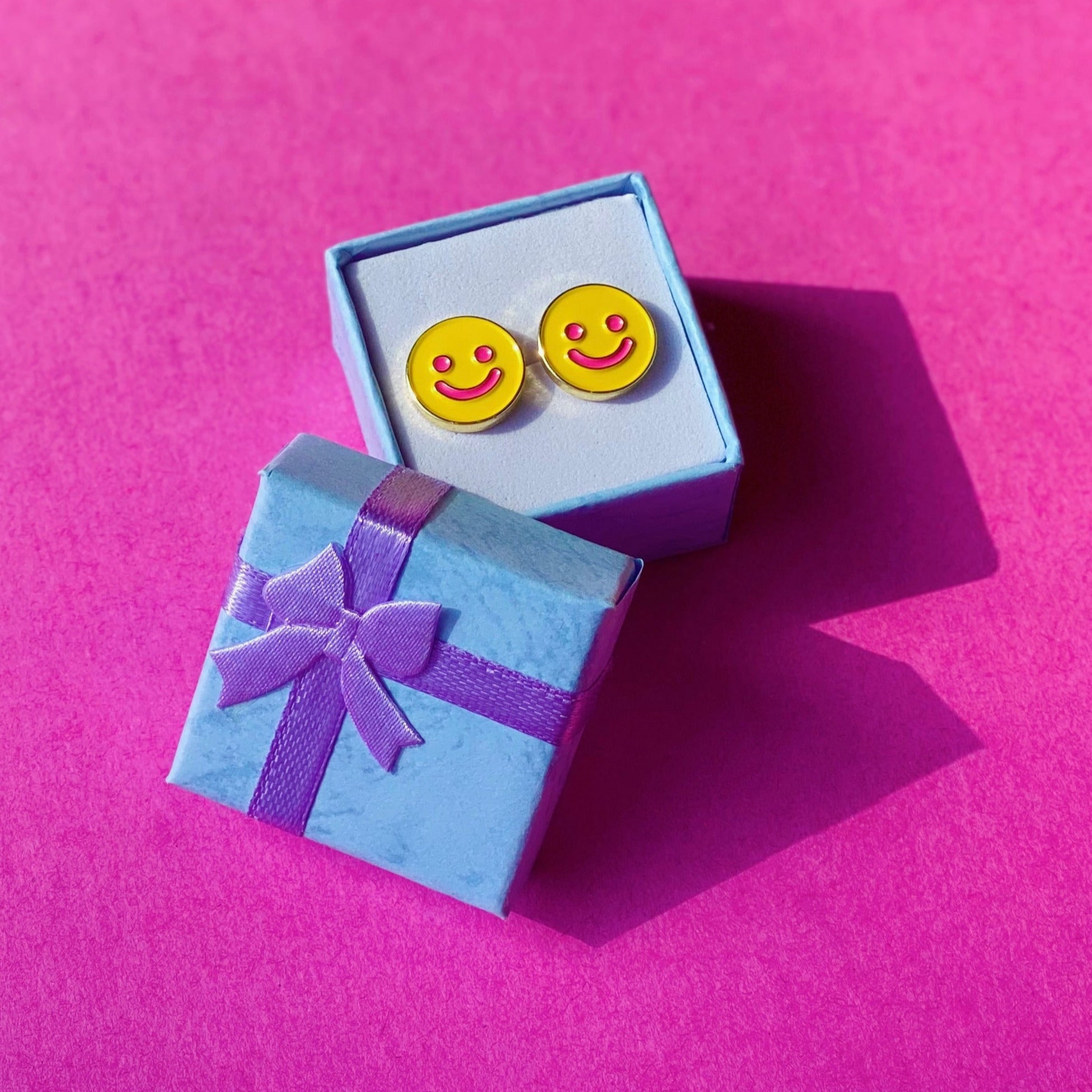 smiley earrings sitting in small gift box, gift box lid has a tiny bow on top and is leaning on box